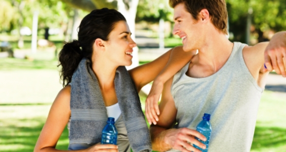 Romantic young couple holding bottles of water at the park
